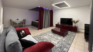 A modern living room with a sofa, a TV, a coffee table, and a patterned rug. - Apartment with terrace, 48sqm. for max. 4 persons (Bühlertal)
