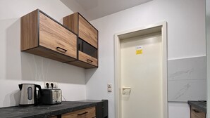 A modern kitchen with wooden cabinets, a black countertop, a coffee maker, and a toaster. - Apartment with terrace, 48sqm. for max. 4 persons (Bühlertal)
