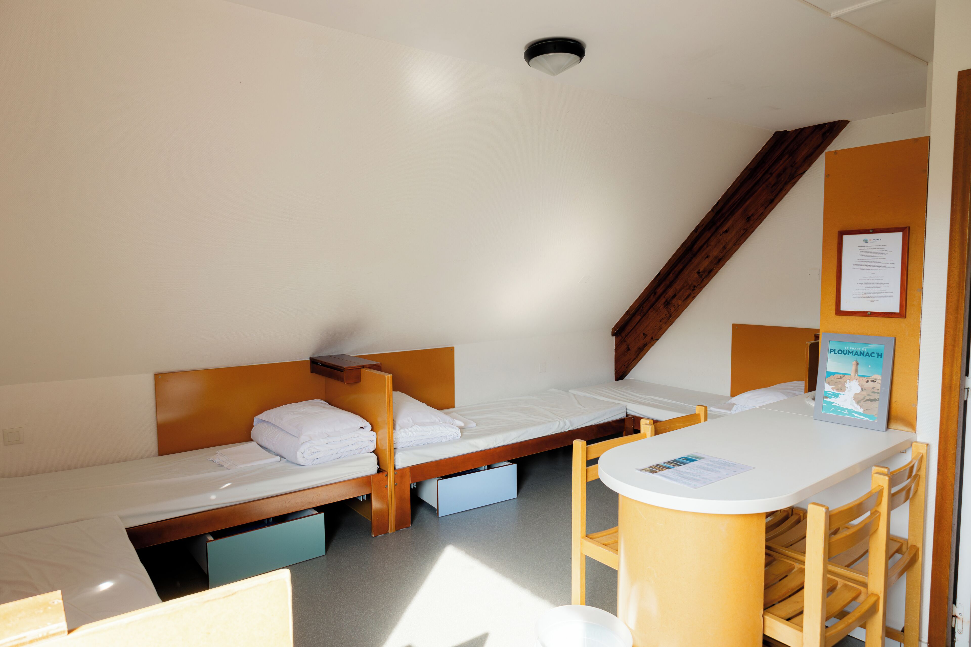 Una habitación de hotel compacta con dos camas individuales, una mesita pequeña y una silla.