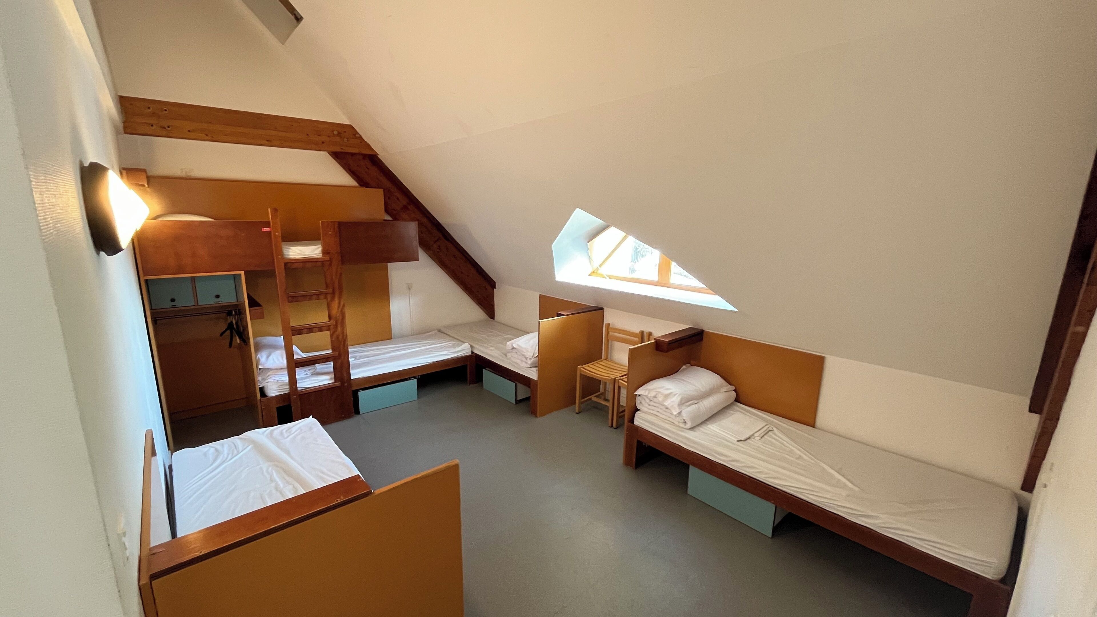 Un dormitorio con literas, un escritorio, una silla y una ventana pequeña.