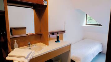 A small, tidy room with a single bed, a white sink, and a mirror above it.
