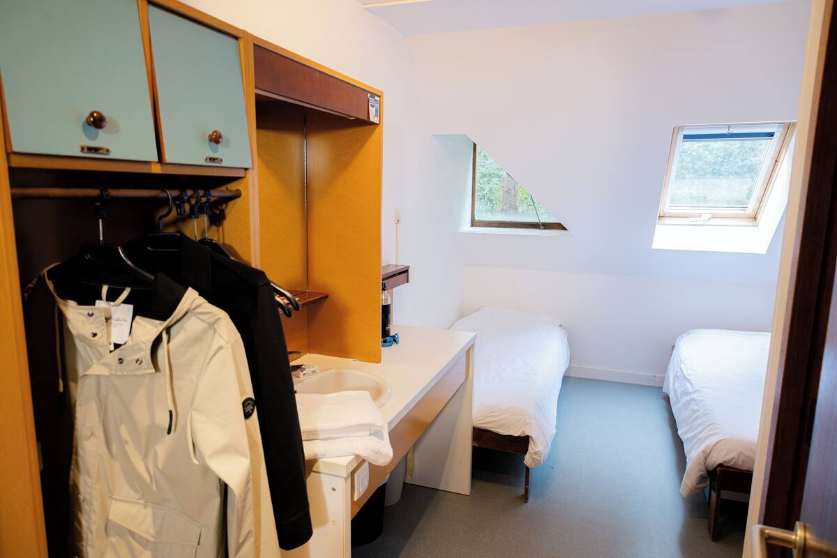 Habitación de hotel con cama, escritorio con silla, armario y ventana.