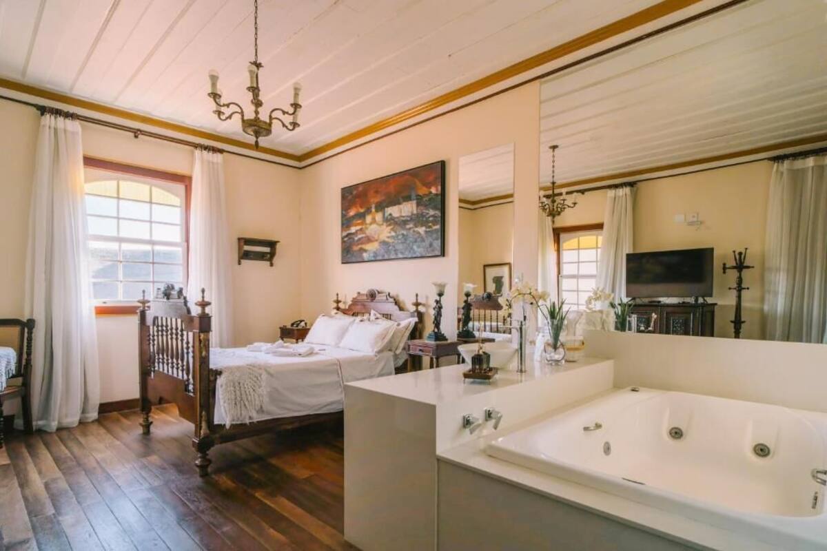 Une chambre à coucher avec un lit en bois, une grande fenêtre, un tableau et un téléviseur.