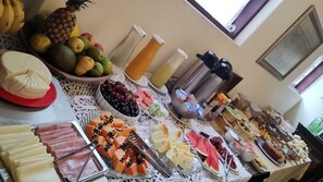 Een buffet met diverse etenswaren, zoals fruit, kazen en vleeswaren.