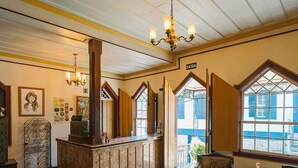 Um quarto com um balcão de atendimento em madeira, um candelabro, lareira e amplas janelas com vista.