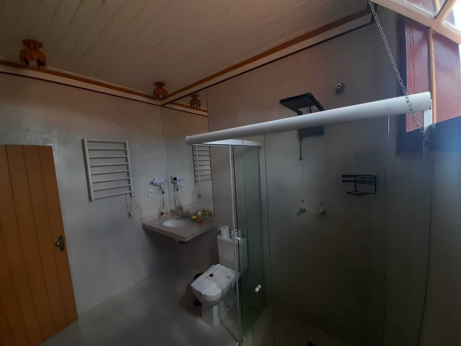 A bathroom with a toilet, a sink, a glass shower enclosure, and a towel rack.