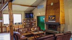 Ein gemütlicher Aufenthaltsraum mit Ledersofas, einem Kamin und einem Bücherregal voller Bücher.