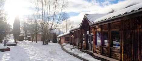 Un edificio de madera cubierto de nieve con un banco al frente.