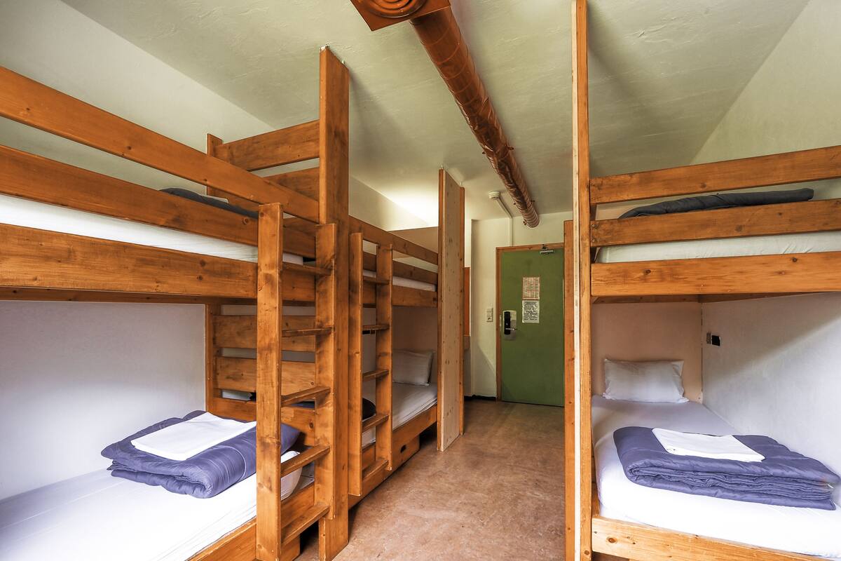 Una habitación con literas, una puerta verde y techo de madera.