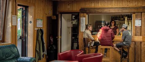 Un interior de madera con una zona de bar, sillas rojas y un mostrador de madera.