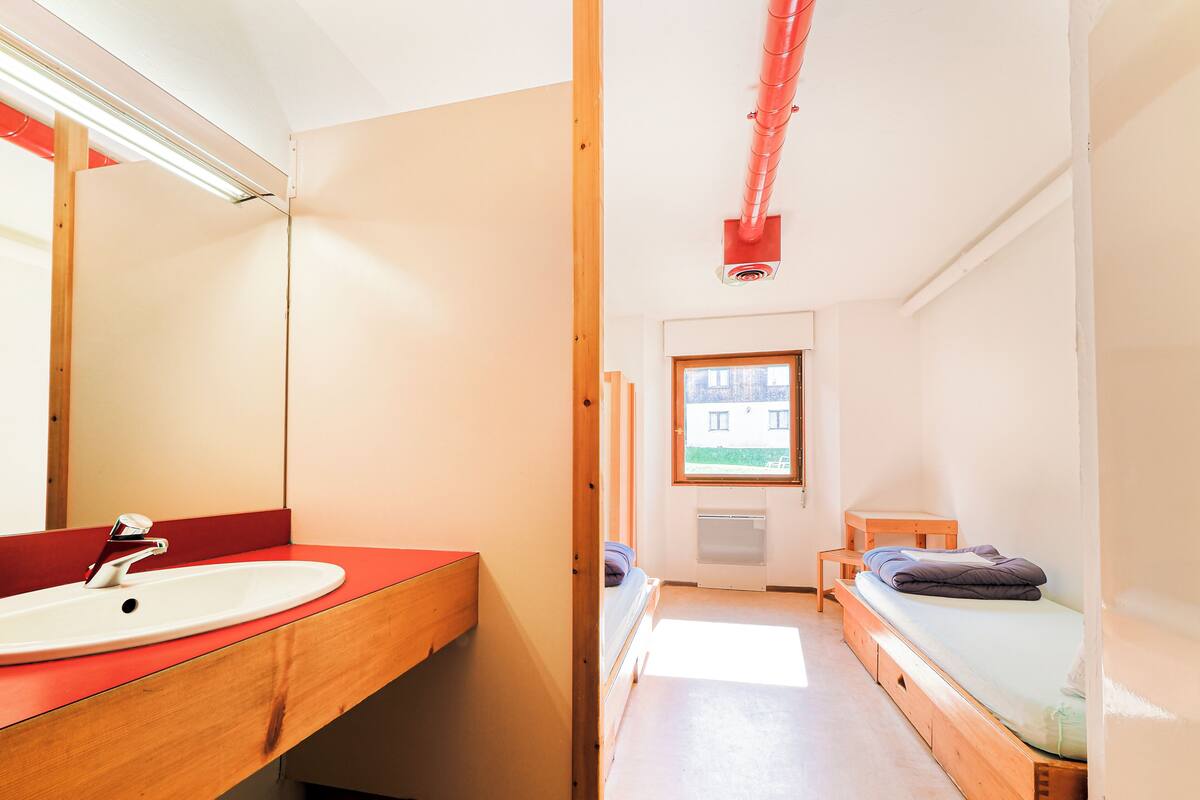 Una habitación pequeña y luminosa con un tocador de madera, un espejo y una ventana.