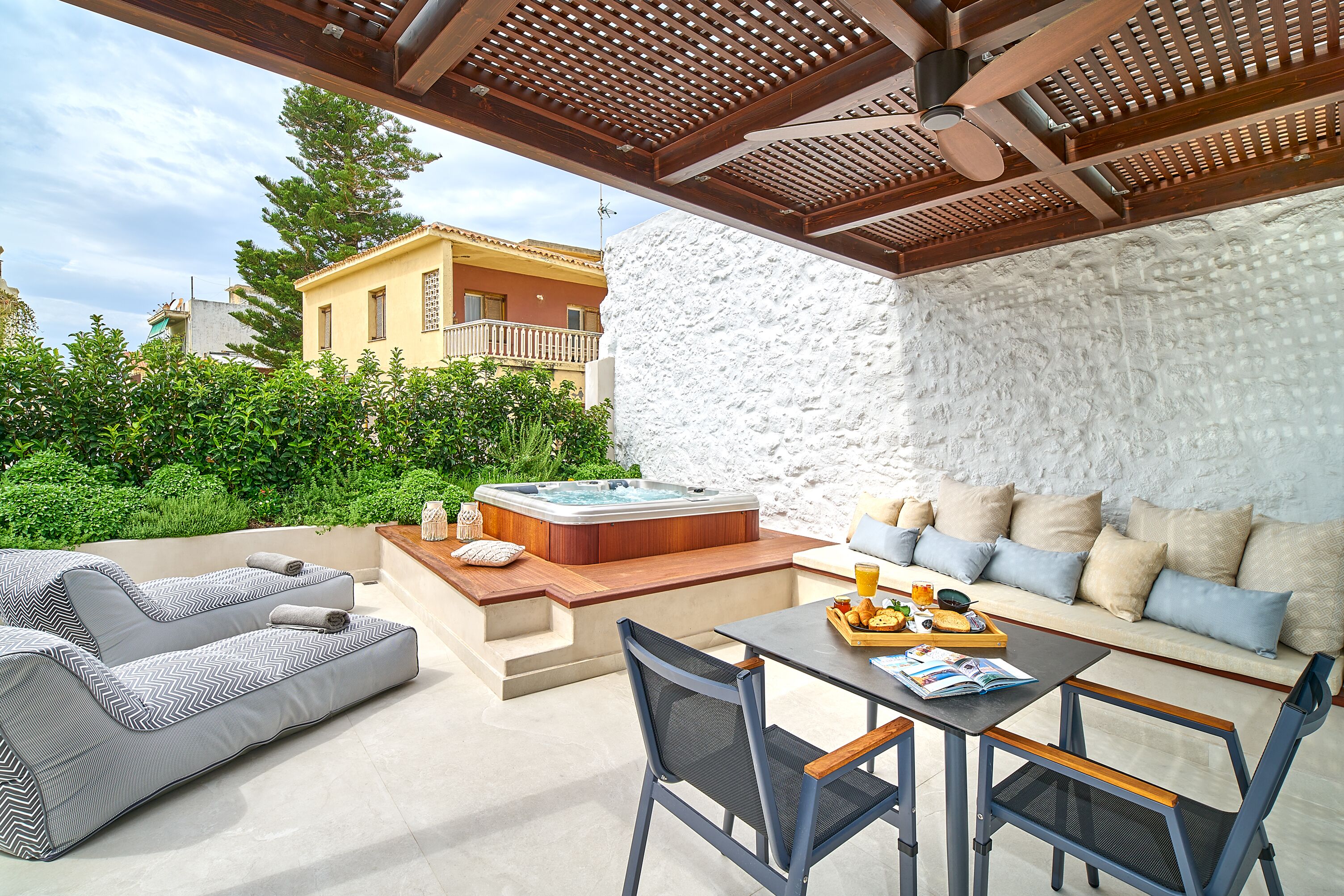 Un patio al aire libre con jacuzzi, un sofá y una mesa de comedor.