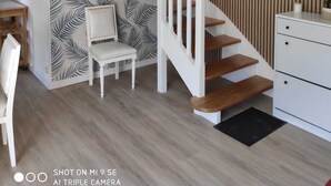 Una escalera con barandillas blancas y escalones de madera, una silla, una mesita y un armario blanco.