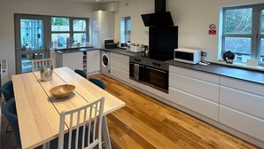 A modern kitchen with a dining area, wooden flooring, and large windows. - Relaxing Luxury Holiday Home (Llangollen)