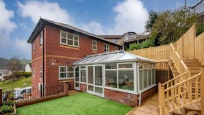 A two-story house with a conservatory, a wooden deck, and a staircase. - Relaxing Luxury Holiday Home (Llangollen)
