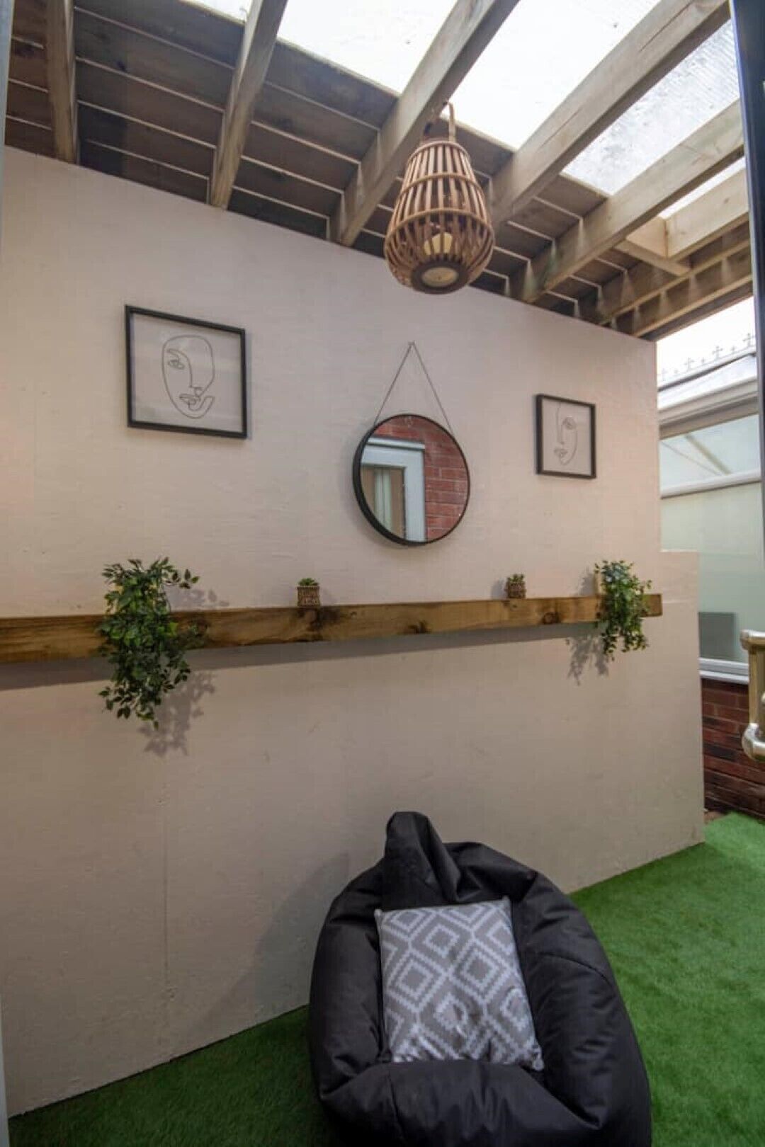 Ein Zimmer mit Holzbalkendecke, einem Wandspiegel und zwei gerahmten Kunstwerken.