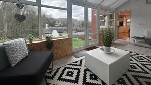 A modern living room with a large window, a sofa, a coffee table, and a view of the outdoors. - Relaxing Luxury Holiday Home (Llangollen)