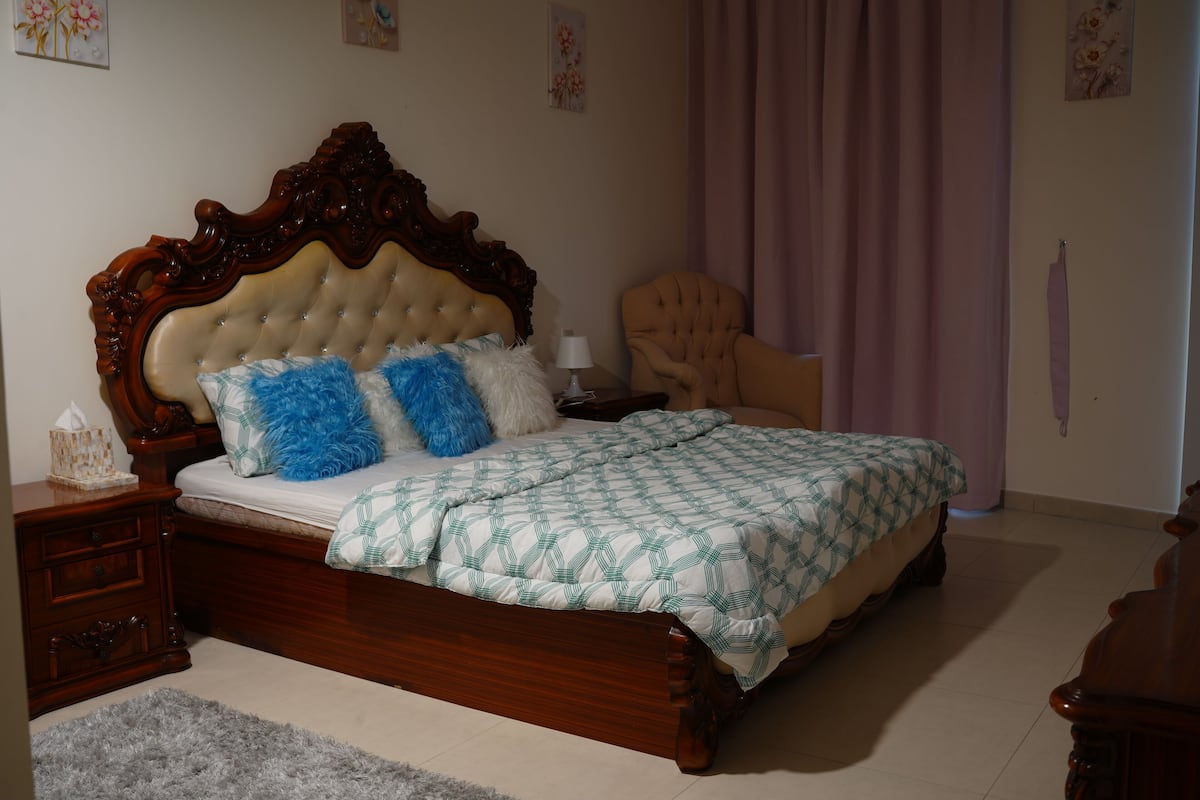 Une chambre à coucher avec un lit en bois, une table de chevet, une chaise et une lampe.