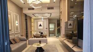 A modern living room with a sofa, a coffee table, and a dining area. - Mirdif Hills Apartaments (Dubai)