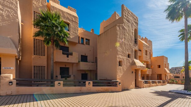 A building with a traditional architectural style, featuring multiple balconies and a paved courtyard. - Coto Real 2408 Kiznos Sun & Relax (Manilva)