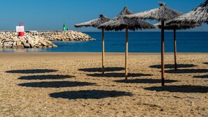 A beach with thatched umbrellas and a rocky breakwater. - Coto Real 2408 Kiznos Sun & Relax (Manilva)
