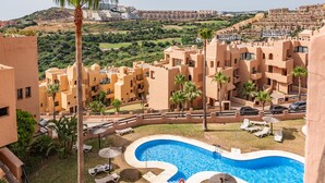 A resort with a swimming pool, palm trees, and a view of a hilly landscape. - Coto Real 2408 Kiznos Sun & Relax (Manilva)