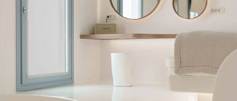 A modern bathroom with a large bathtub, a vanity with a mirror, and a window with a view.