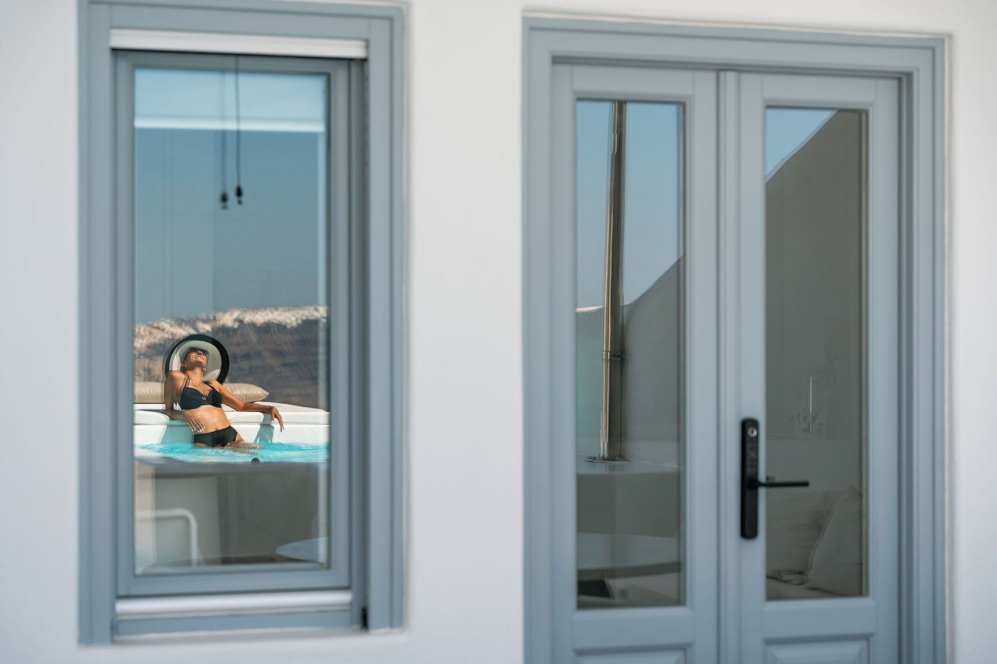 A room with a large window, a door with a handle, and a view of a swimming pool.