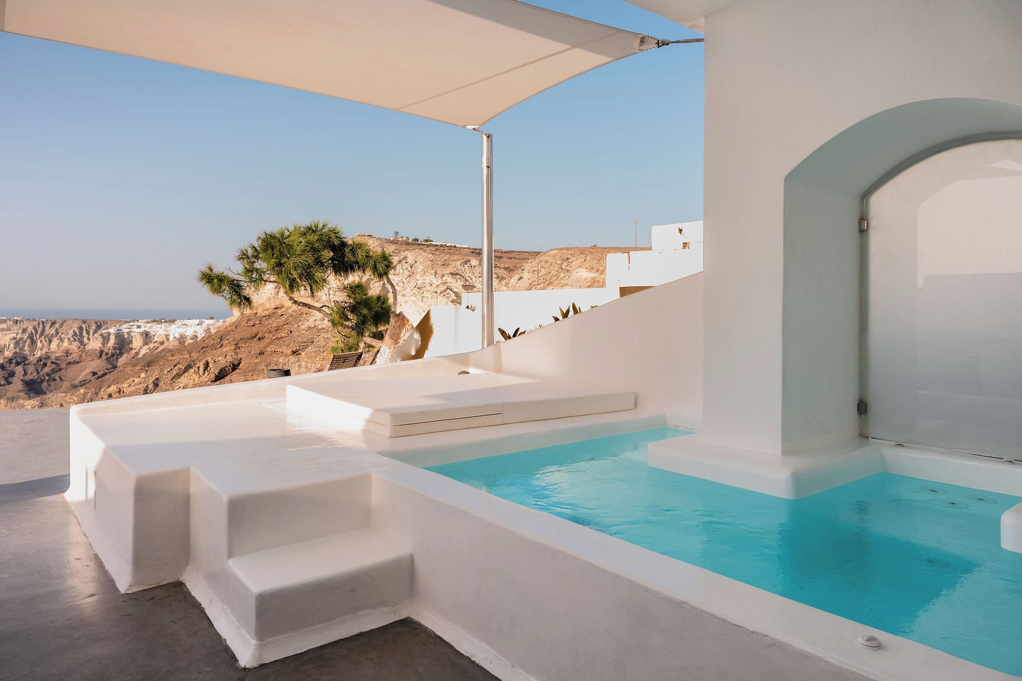 A modern outdoor pool area with a clear view of the coastline.