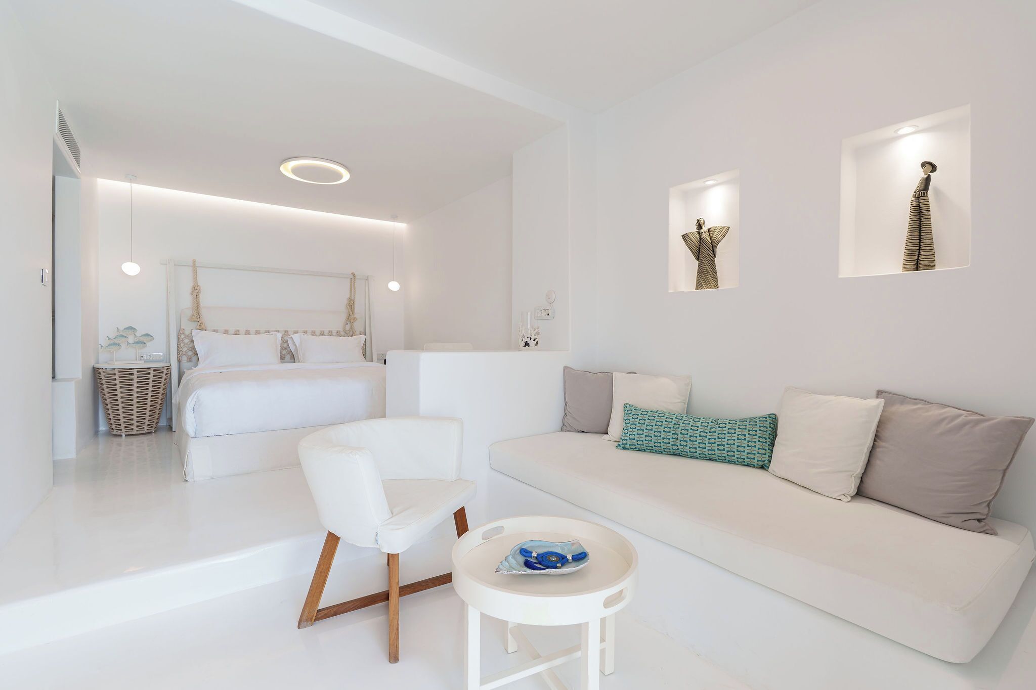 Un soggiorno moderno e minimalista con un divano bianco, una poltrona bianca e un piccolo tavolino bianco.