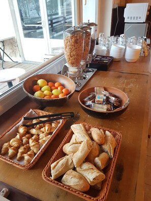 Un bufé de desayuno con cruasanes, pan y fruta.