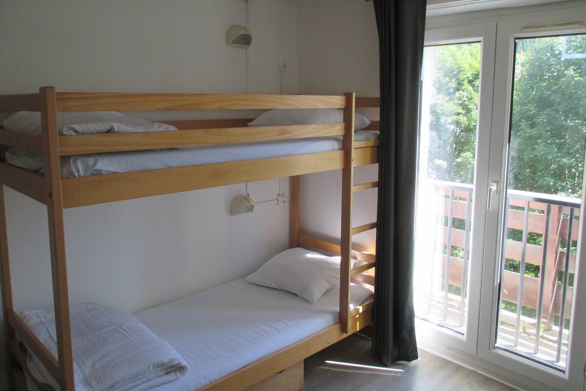Ein Schlafzimmer mit Etagenbetten, einem Fenster und einer Tür.