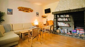 Un salon chaleureux avec une cheminée en pierre, un canapé, une table basse et des fauteuils en osier.