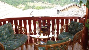A wooden deck with wicker chairs and a table, overlooking a forested valley. - The Sharkov House (Satovcha)