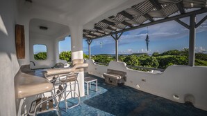 A modern outdoor seating area with a view of lush greenery and a distant island. - La Casona Blanca Location Location  (Esperanza)