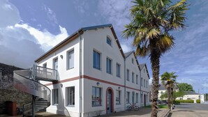 A two-story building with a spiral staircase, a red door, and a bicycle parked outside. - Auberge de Jeunesse HI Cherbourg (Cherbourg-en-Cotentin)