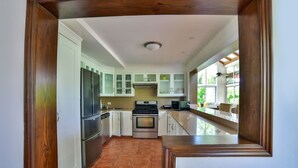 A kitchen with white cabinets, stainless steel appliances, and a large window providing natural light. - casa de campo villa 204 (La Romana)