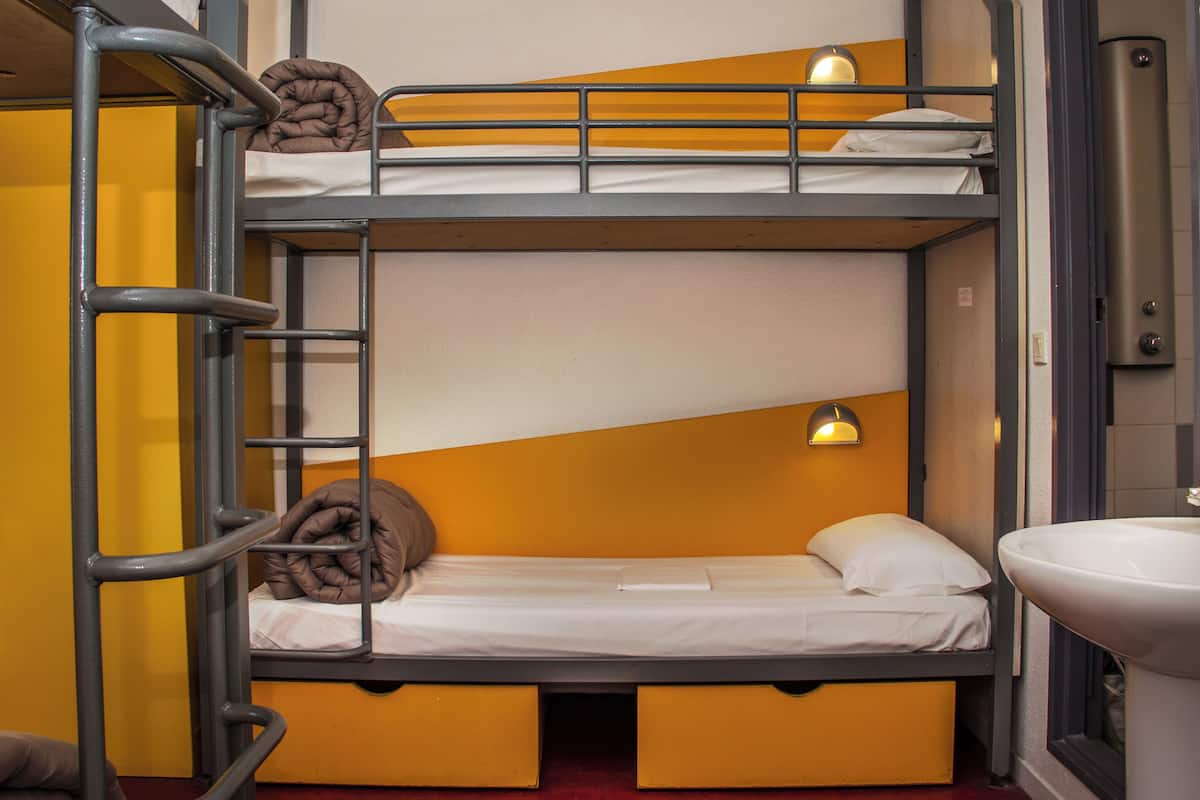A bunk bed room with a ladder, a sink, and a window.