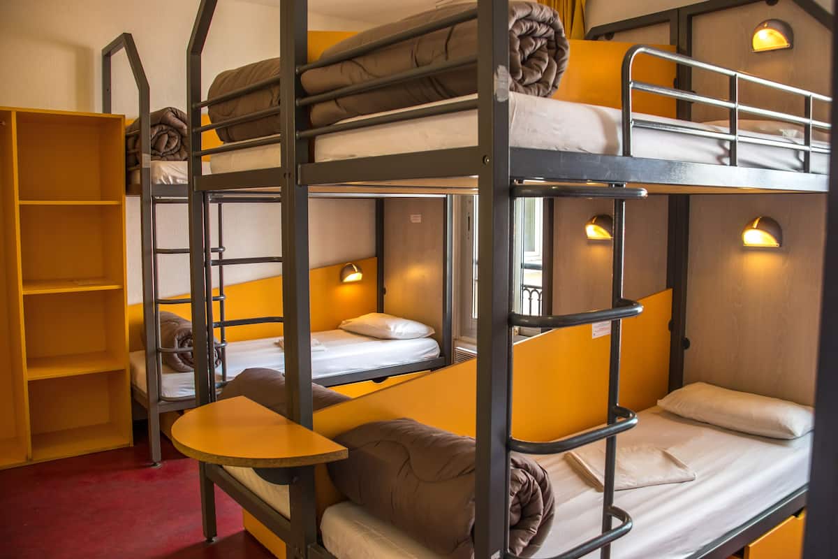 A bunk bed room with a wooden bunk bed, a yellow shelf, and a small table.