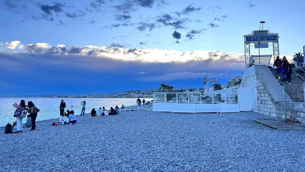 A pebbled beach with people relaxing and a lifeguard tower in the background. - Auberge de Jeunesse HI Nice - Les Camélias (Nice)