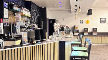 A modern bar area with a counter, bar stools, and a variety of bottles and glasses on shelves.
