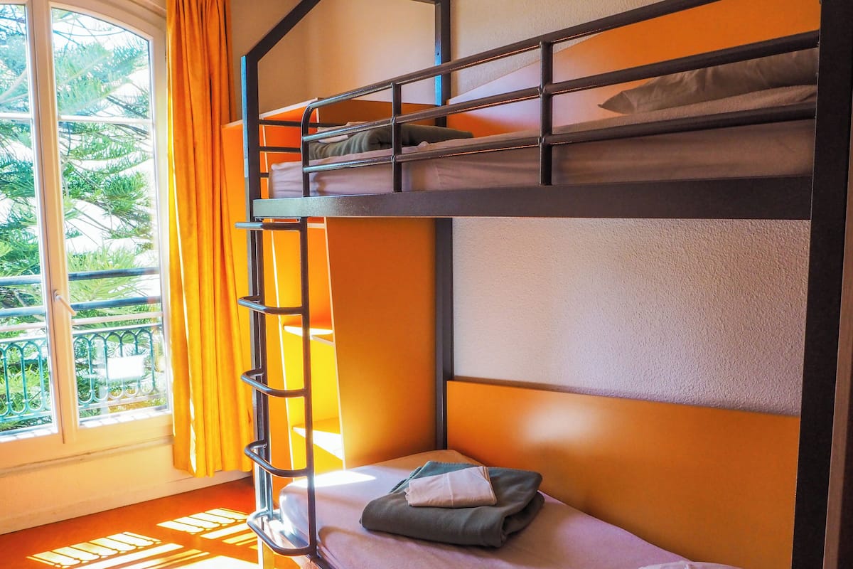 A bunk bed room with a window and curtains.