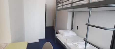 A bunk bed room with a desk and chair, a small table, and a blue carpet.