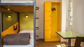 Un dormitorio con literas, un armario amarillo, un escritorio y una ventana.