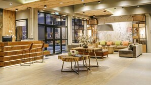 Un vestíbulo amplio con mobiliario de madera, un mostrador de recepción y una zona de estar con sofá y sillones.