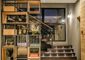 Un intérieur moderne agrémenté d’un escalier en bois, de rampes en métal et de divers éléments décoratifs, notamment des plantes et des paniers.