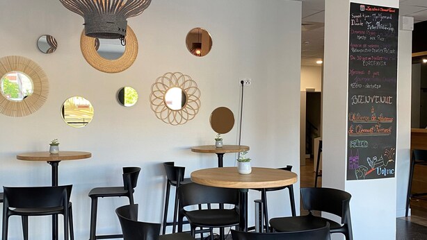 A modern cafe interior with round tables, black chairs, and decorative wall mirrors. - Auberge de jeunesse HI Clermont-Ferrand (Clermont-Ferrand)