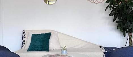 Una sala de estar con un sofá, una mesita redonda y una planta en maceta.