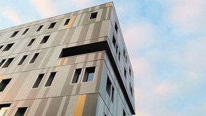 A modern building with a unique angular design, featuring multiple windows and a patterned facade. - Auberge de jeunesse HI Clermont-Ferrand (Clermont-Ferrand)