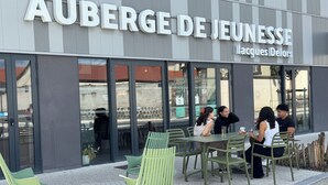 An outdoor seating area with tables and chairs in front of a building with a sign reading 'AUBERGE DE JEUNESSE Jacques Delors.' - Auberge de jeunesse HI Clermont-Ferrand (Clermont-Ferrand)